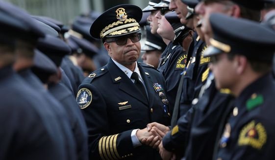 James Craig and police officers in uniform, one shaking hands with another, appearing to be in a formal or ceremonial setting.